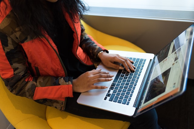 lady in a red and black jacket using a laptop