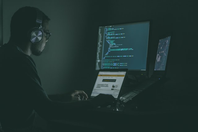 a person operating a laptop in front of a monitor